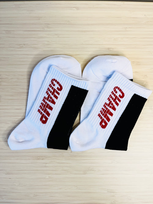 White socks with black bands and red text on a wooden surface