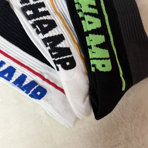 Three pairs of socks with 'Champ' branding on a beige surface