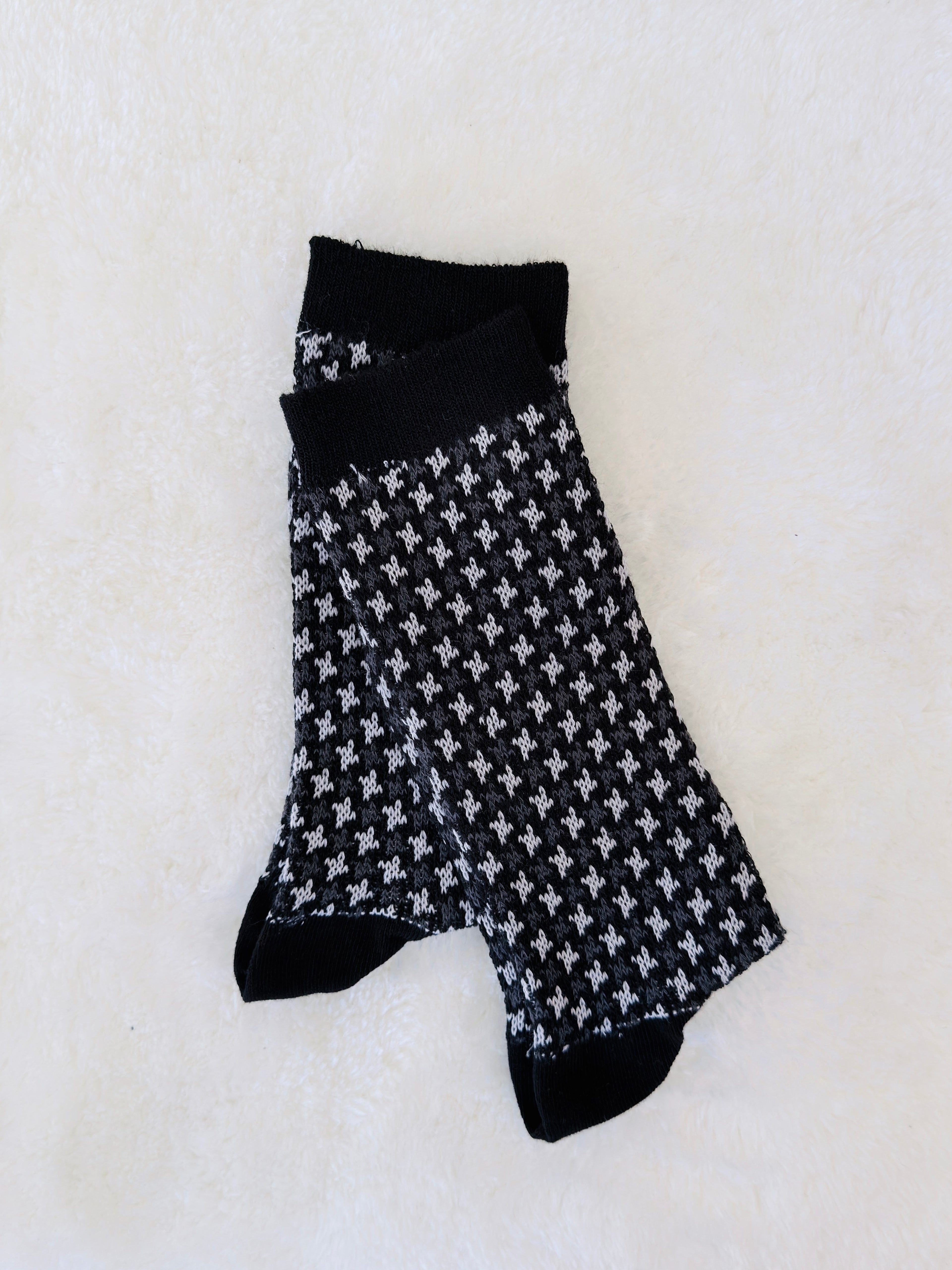 Pair of black socks with white pattern on a light gray background