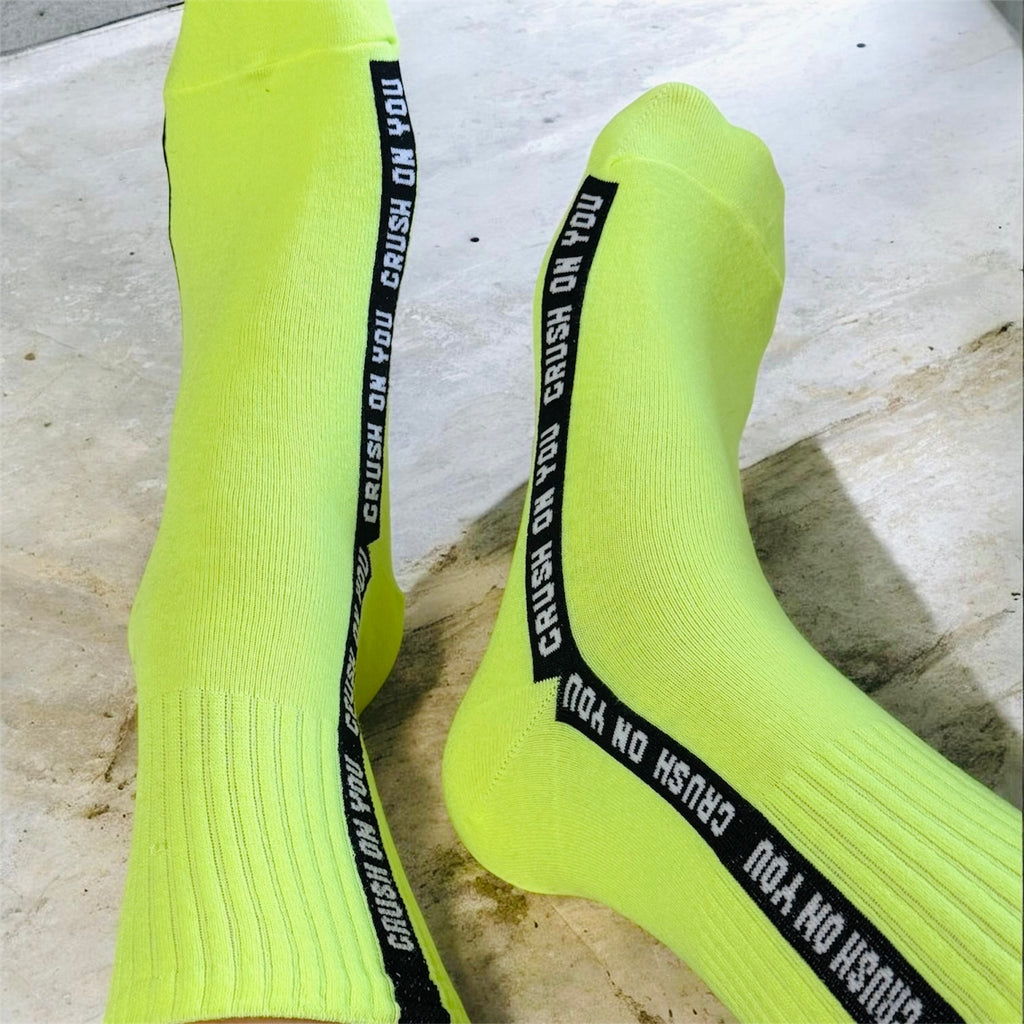 Neon yellow socks with black text bands on a concrete floor.