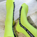 Neon yellow socks with black text bands on a concrete floor.