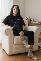 Woman sitting on a white armchair wearing patterned socks indoors.