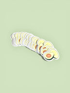 A stack of cute avocado die-cut stickers displayed on a soft green background.